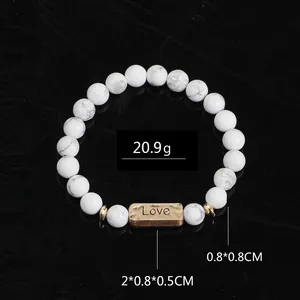 Detail of white marble stone bead bracelet with Love engraved bronze charm and black reflection