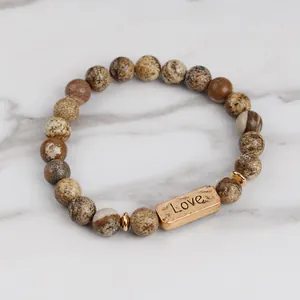 Macro detail of natural stone beaded bracelet with Love engraved vintage metal plate