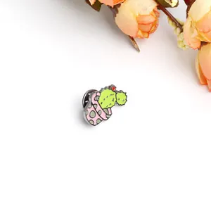 Primer plano de un pin esmaltado de cactus verde con flores rojas en una maceta rosa
