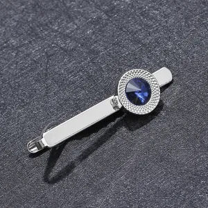 Detailed view of silver tie clip featuring a round navy blue zircon and textured edge