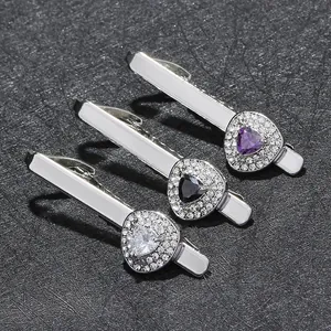 Close-up of three silver tie clips featuring purple, black, and white zircon stones