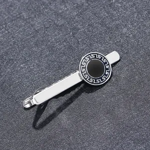 Macro detail of silver tie clip with black enamel circle and classic Greek key pattern