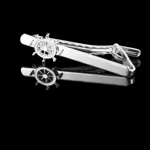 Close-up of silver necktie clip featuring a nautical ship wheel design with mirror reflection
