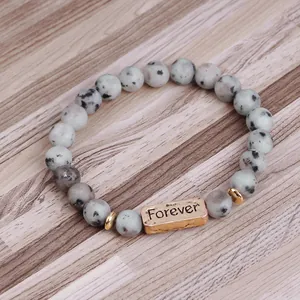 Detailed macro of a beaded natural stone bracelet with a gold metal Forever plaque