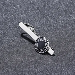 Macro detail of silver tie clip featuring a black round disk with Greek Key pattern