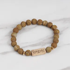 Macro detail of natural stone beaded bracelet with Forever engraved rose gold charm