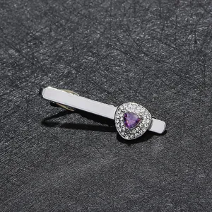 Close-up of silver tie clip featuring a triangular purple zircon and sparkling crystals