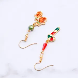 Detailed close-up of asymmetric Christmas earrings with enamel glove and stocking charms
