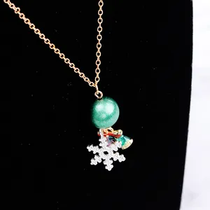 Detailaufnahme der Weihnachtshalskette mit grüner Glitzerkugel und silbernem Schneeflocke