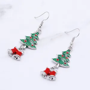 Detail of Christmas tree and red bell dangle earrings with festive green enamel finish