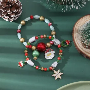 Close-up of Christmas charm bracelets with Santa and snowflake pendants on pine needles