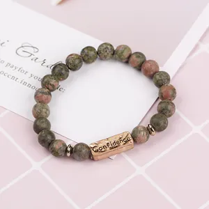 Detail of natural green stone beaded bracelet featuring a bronze Confidence charm