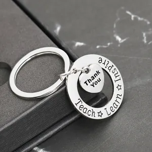 Macro shot of silver heart keychain with Thank You and Inspire engraving in a gift box