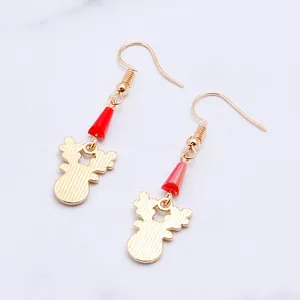 Close-up of golden reindeer earrings with red beads and textured finish on marble