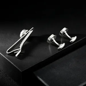 Macro detail of silver-tone cufflinks and tie clip set on professional black display