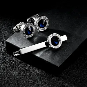 Detail of silver cufflinks and tie clip set with blue crystals on black display