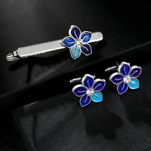 Detailed view of silver flower cufflinks and tie clip set with blue enamel and crystal