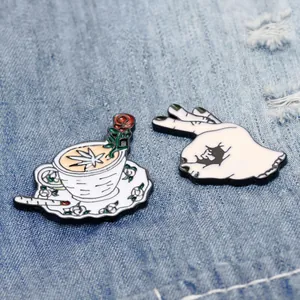 Detail of enamel pins featuring a rose coffee cup and hand gesture with bat icon
