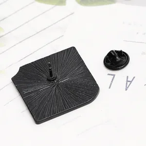 Dettaglio del retro della spilla a libro in metallo nero con base lavorata e chiusura a farfalla