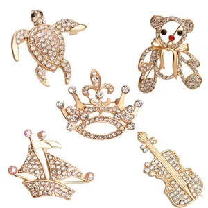 Set di 5 spille dorate con strass raffiguranti tartaruga, orso, corona, violino e barca