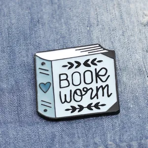 Spilla smaltata a forma di libro con cuore e foglie su una giacca di jeans blu