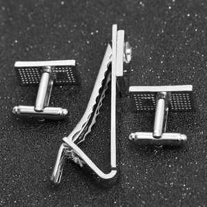 Macro shot of silver metal tie clip and cufflinks set with crystal inlays and texture
