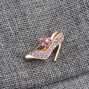 Close-up of golden high heel brooch with pink rhinestones and a central crystal flower