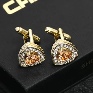 Detailed close-up of gold triangle cufflinks with amber crystal and micro-pavé zircons