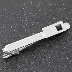 Close-up of polished silver tie clip with square black gemstone on a textured background