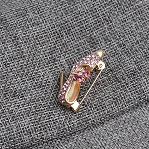 Detail of high heel brooch with purple rhinestones and pink crystal flower on gold base
