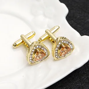 Detailed macro view of gold triangular cufflinks with amber zircon and crystal accents