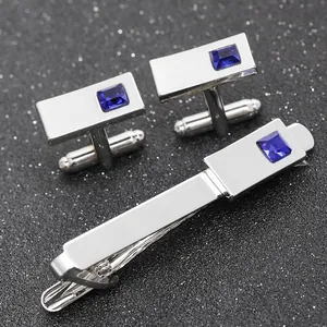 Close-up of silver cufflinks and tie clip set with square blue crystal inlays