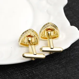 Macro shot of gold cufflinks with amber zircon inlays on a white decorative plate