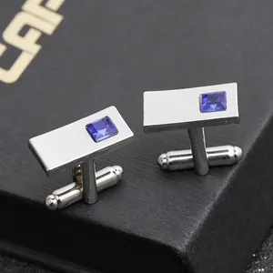 Detailed close-up of silver French cufflinks with inlaid blue gemstone on black jewelry box