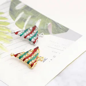 Detailed view of gold and silver Christmas tree brooches with red and green enamel and crystals