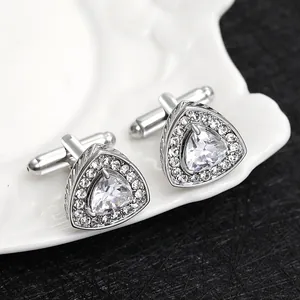 Macro shot of silver triangle cufflinks with zircon inlay on a white porcelain plate