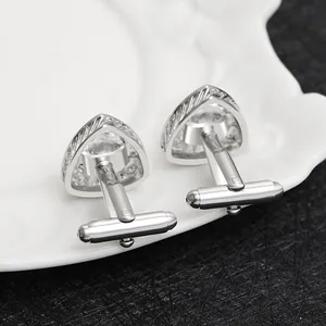 Detailed close-up of silver men cufflinks with triangle zircon and hollow spiral carving