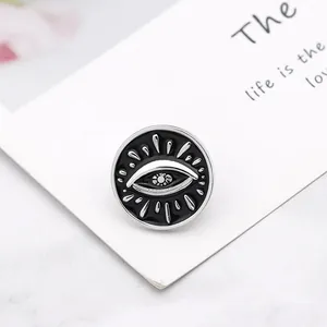 Punk black round evil eye enamel pin with silver metal sunburst details on card