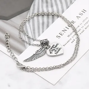Macro shot of silver heart pendant with angel wing and engraved memorial message