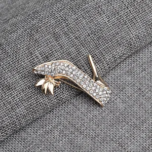 Close-up detail of high heel brooch with sparkling rhinestones on golden alloy