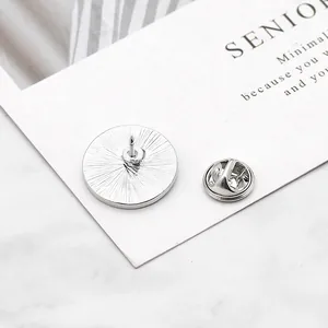 Polished silver metal brooch backings with pin and butterfly clutch on card