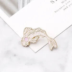 Detail shot of white and pink koi fish enamel brooch with gold trim on marble background