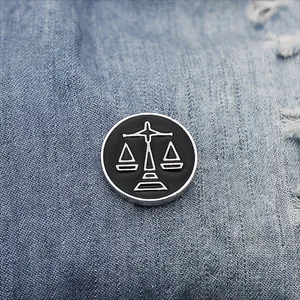 Detailed close-up of a Libra zodiac enamel pin on blue denim fabric background