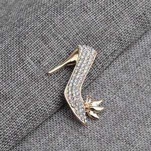 Detailed macro view of gold stiletto heel brooch with sparkling white rhinestones