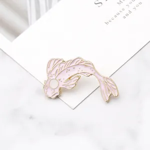 Detailed close-up of pink and gold koi fish enamel brooch on marble background