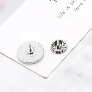 Detail of silver zodiac pin back featuring butterfly clasp and sunburst texture