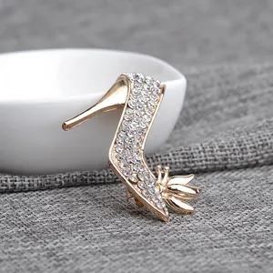 Detailed macro of gold-plated high heel brooch featuring sparkling rhinestones and floral charm