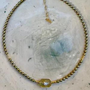 Details einer olivgrünen Perlenkette mit gelbem Edelstein und Markise-Zirkonia-Anhänger