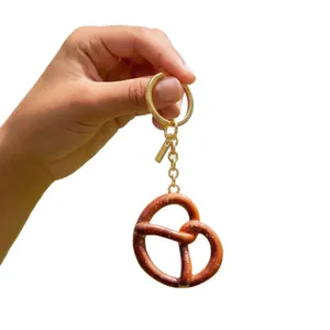 Portachiavi pretzel realistico con anello dorato e consistenza di sale su fondo bianco