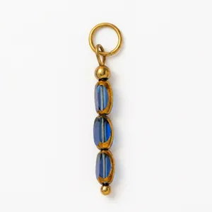 Dettaglio di un pendente placcato oro 18K con perline ovali blu scuro su uno sfondo bianco